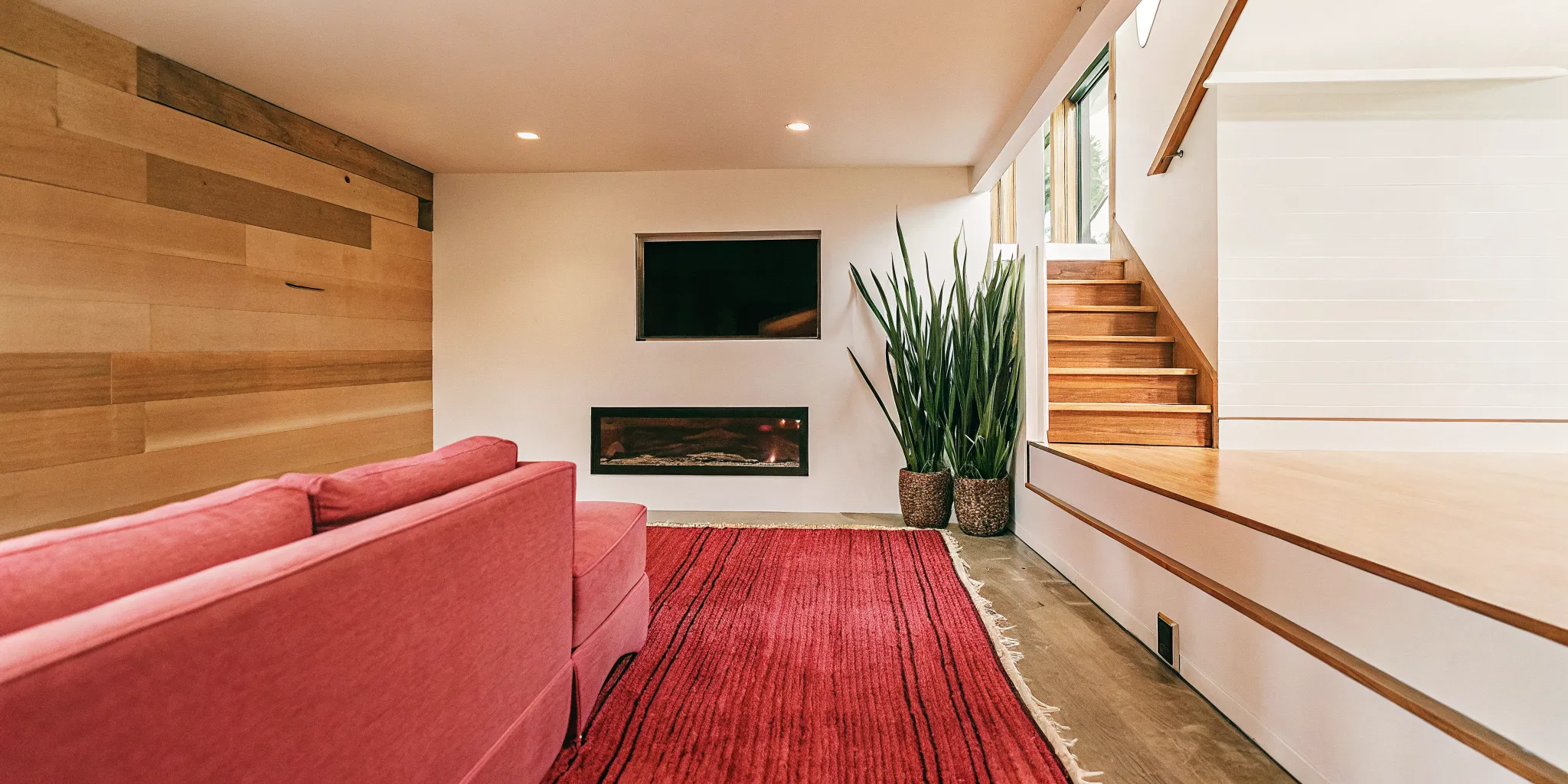 Professionally finished basement in Denver with a modern living area, fireplace, and custom wood accents.