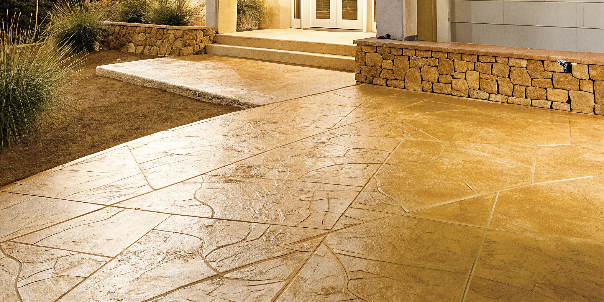 Professionally installed stamped concrete patio with a natural stone pattern by a home's entrance.