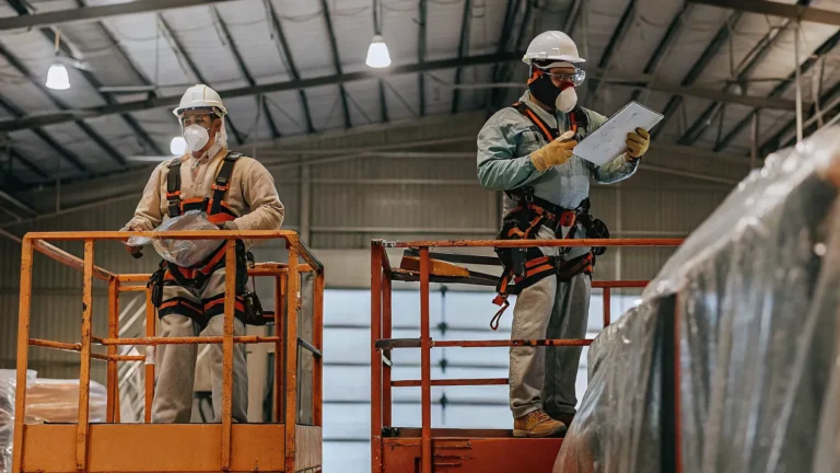 Painting crew in protective gear preparing a warehouse for painting with scissor lifts and protected inventory