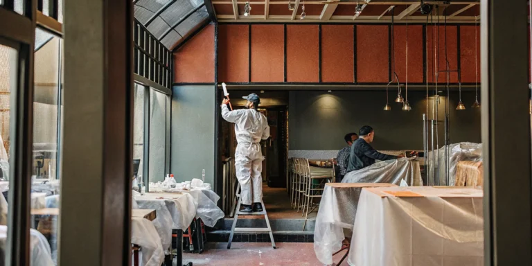 Professional commercial painters working in a Denver restaurant with tables covered