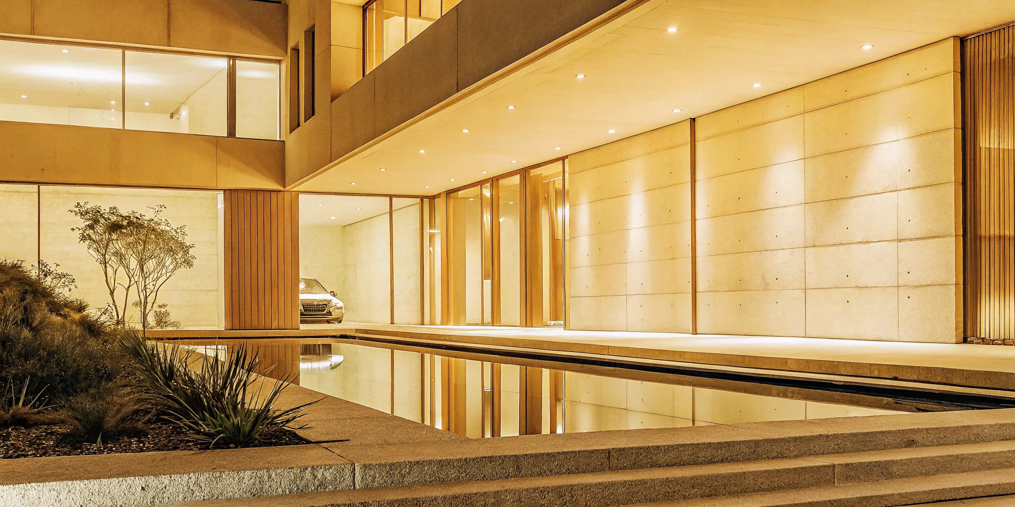 Smart luxury home exterior with automated lighting highlighting its modern architecture and landscaped entrance.